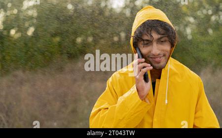 Arabic man holding umbrella out in the rain talking on a mobile phone Stock Photo