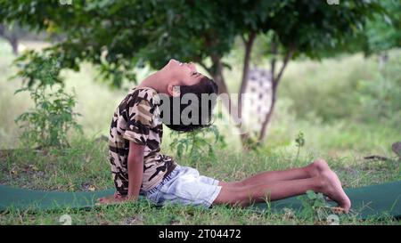 Happy small children sitting in lotus position on comfortable mat with joyful and smiling face, practicing together yoga breathing exercise, doing asa Stock Photo