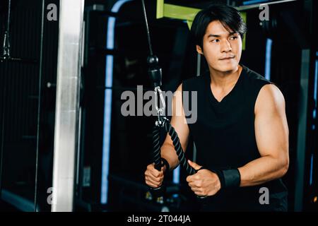 Young man performing cable triceps pulldowns to build muscle and strength Stock Photo