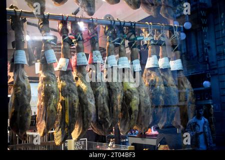 Cured Spanish hams hanging in a shop window. Barcelona, Catalonia, Spain. Stock Photo