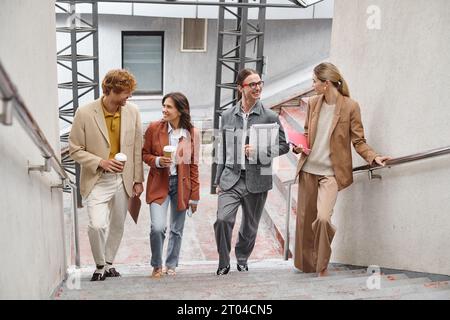 happy young team members walking upstairs talking and smiling at each other, coworking concept Stock Photo