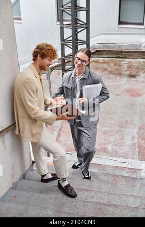 two young man having break outdoors smiling and discussing their paperwork, coworking concept Stock Photo