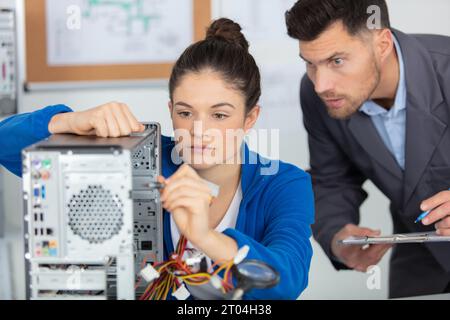 supervisor watching young female apprentice working on computer Stock Photo