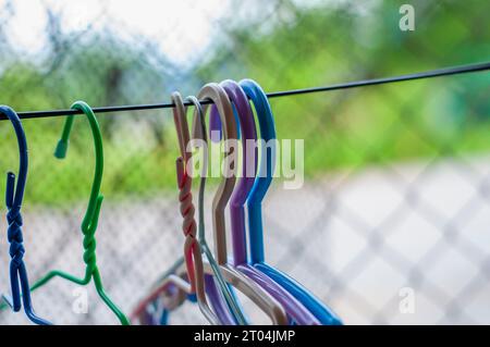 Hangers of various colors hung on a clothesline made of wires blurred background, It is a way of life for people in rural areas far from civilization Stock Photo