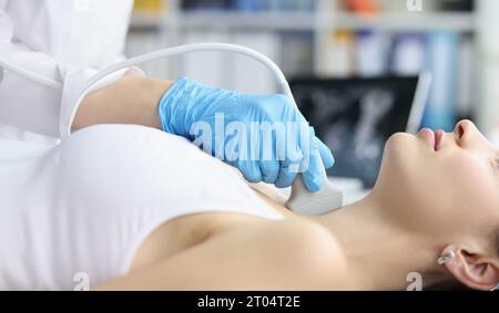 Woman receives ultrasound of thyroid gland from doctor Stock Photo