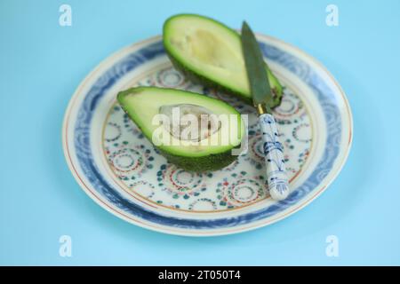 Fresh green sleced avocado on the plate with blue bakground Stock Photo