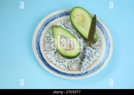 Fresh green sleced avocado on the plate with blue bakground Stock Photo