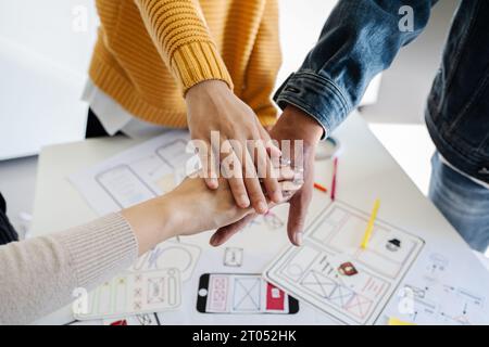 Asian ux developer and ui designer team stacking hands together, celebrating completion of project Stock Photo