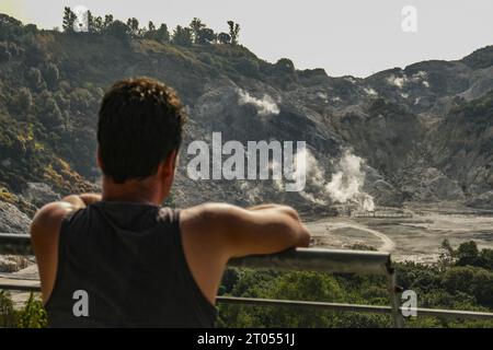 A tourist looks curiously at the crater of the solfatara, it is one of the forty volcanoes that make up the Phlegraean Fields; it is located about three kilometres from the centre of the city of Pozzuoli, it is the epicentre of the seismic swarm that has occurred in recent days, the strongest tremor the day before yesterday of magnitude 4.2 recorded by the Monitoring Network of the Vesuvius Observatory of the National Institute of Geophysics and Volcanology (INGVA generic view of the solfatara, it is one of the forty volcanoes that make up the Phlegraean Fields; it is located about three kilom Stock Photo