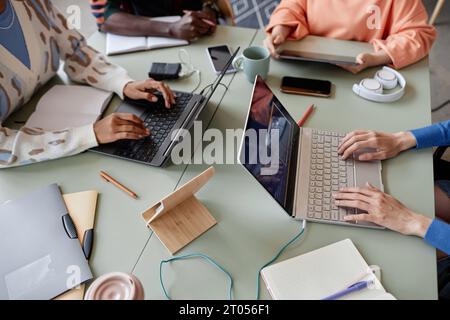 Top view closeup of diverse young team using computers at meeting table in office, copy space Stock Photo
