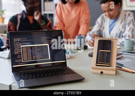 Close up of laptop and smartphone with programming code lines on screen, copy space Stock Photo