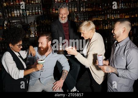 cheerful bearded man and african american woman laughing near multiethnic colleagues in bar Stock Photo