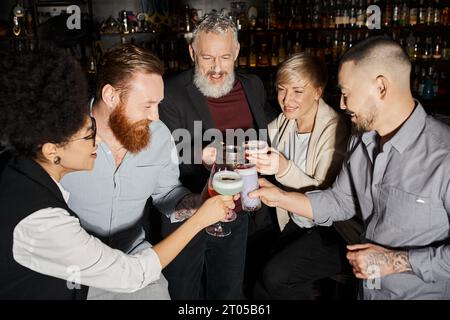 joyful and successful multiethnic business team clinking glasses while spending time in cocktail bar Stock Photo