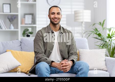 Portrait of a smiling young African American man sitting on a couch and smiling at the camera. Stock Photo