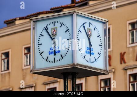 two faces of the cube shaped art deco style clock on the harbourside at sibenik croatia show six minutes to six Stock Photo