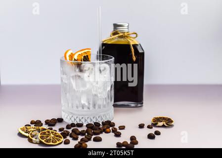 Cold brew coffee in a bottle with transparent glass full of ice on green leaves background Stock Photo