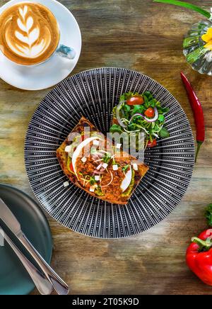 Smashed avocado with poached eggs, red pepper pesto and pickle shallot on toast top view Stock Photo