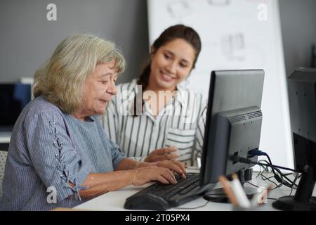Elderly woman typing on computer under control on teacher Stock Photo