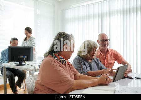 Group of seniors learning how to use applications on tablet computer Stock Photo