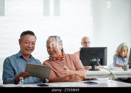 Serious couple attending computer class to learn how to use application on digital tablets Stock Photo