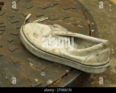 Close-up of a white Vans shoe on a sewer grate Stock Photo