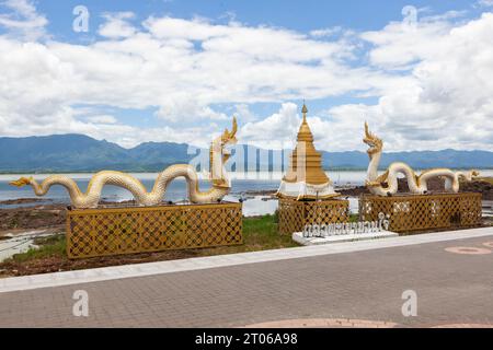 Phayao Town landmark in North Thailand. Naga statue and golden stupa on Phayao lake and mountains background. Stock Photo