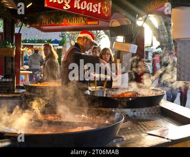 German Christmas market UK SouthBank London food. Hog Roast takeaway alfresco hot steaming sausage & meats in a bun food stall busy with visitors London UK London South Bank Winter food stalls, Hog Roast hot steaming German speciality take away fast food stall Christmas season London SouthBank UK Stock Photo