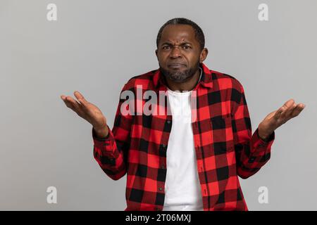Puzzled black bearded man wearing red checkered shirt having uncertain expression Stock Photo