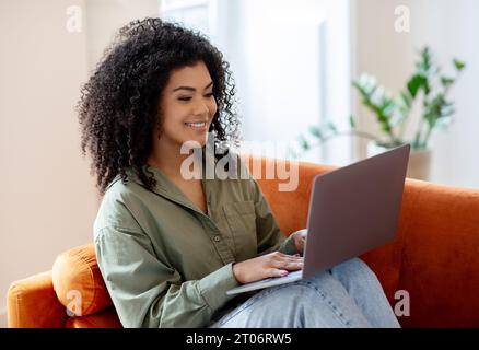 Bushy Woman Working On Laptop PC Sitting In Living Room Stock Photo