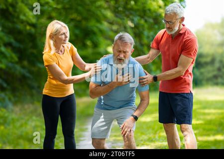 Senior man suffering from heart attack while training with friends in park Stock Photo