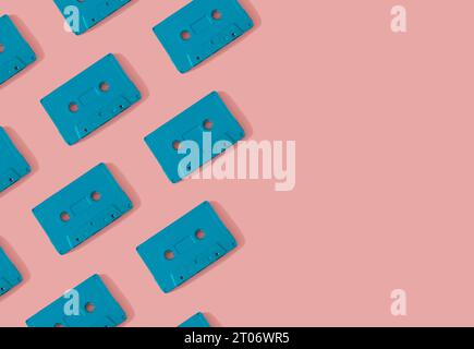Pattern made with retro blue audio cassette tapes on modern pink background. Creative concept of retro technology. 80's aesthetic. Retro vintage audio Stock Photo