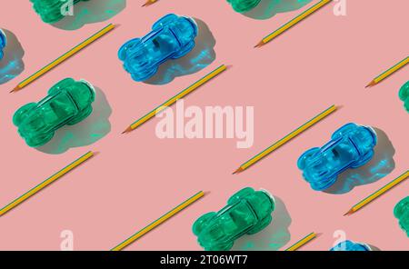 Trendy racing cars pattern made of pencils and pencil sharpeners on pastel pink background with copy space. Minimal school concept. Stock Photo