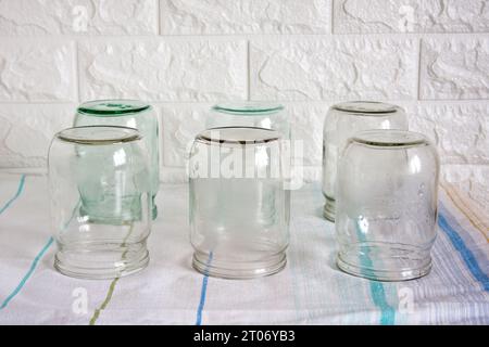 Several clean, empty half-litre glass jars sit upside down on the kitchen table. Time to preserve berries, fruits and vegetables. Stock Photo