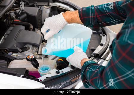 pour antifreeze. the driver pours fluid into the washer reservoir. washer  fluid. glass cleaner. man pouring windshield wiper into car. driver pours  an Stock Photo - Alamy