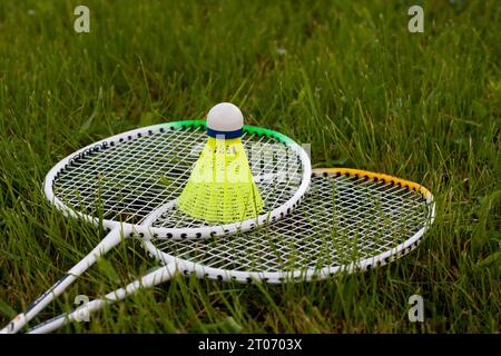 Badminton set yellow shuttlecock and rackets lying on green grass. Sports concept. Active game of badminton outdoors. Sport equipment. Stock Photo