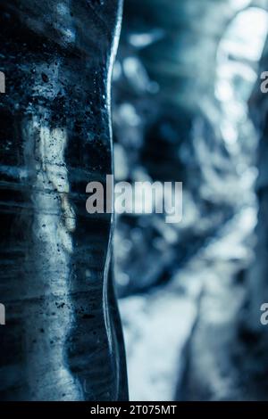 Water dripping from ice rocks in cave, climate change concept. Massive icy blocks melting inside vatnajokull iceberg crevasse, icelandic nature admired through glacier hiking. Stock Photo