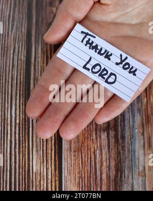 Thank You, LORD, handwritten note in hand over wooden background with ...