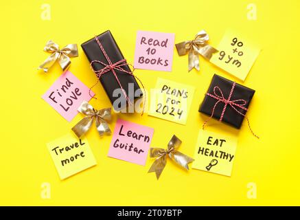 Sticky notes with different goals for 2024, bows and gift boxes on yellow background Stock Photo