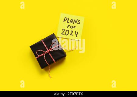 Sticky note with goals for 2024 and gift box on yellow background Stock Photo
