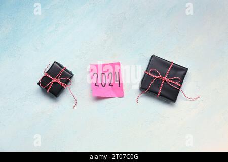 Sticky note with year 2024 and gift boxes on gradient background Stock Photo