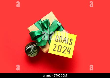 Sticky note with goals for 2024 and gift box on red background Stock Photo