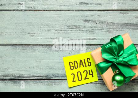 Sticky note with goals for 2024 and gift box on grey wooden background Stock Photo