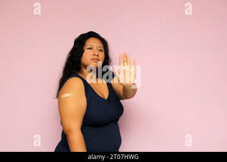 Young body-positive black-haired Latina woman shows her newly vaccinated arm against Covid-19 in the new normal for the oronavirus pandemic Stock Photo