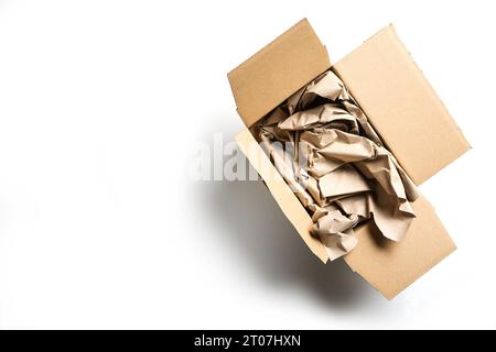 Large packaging for small goods on white, without plastic but natural cardboard box and a lot of paper, waste of resources and trees with many online Stock Photo