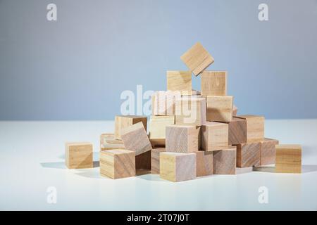 Teamwork with a broad base is the way up, heap of wooden cubes holding one of them on the top, concept for togetherness in business and organizations, Stock Photo