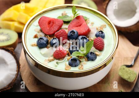 Tasty matcha smoothie bowl served with berries and oatmeal on table, closeup. Healthy breakfast Stock Photo