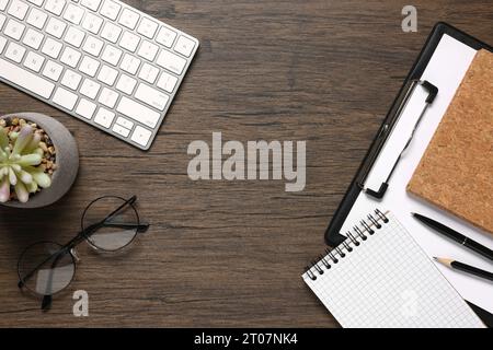 Flat lay composition with computer keyboard and different stationery on wooden desk, space for text. Home office Stock Photo