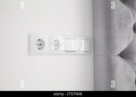 Light switches and power sockets on white wall indoors Stock Photo