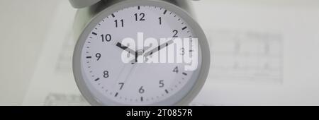 Alarm clock stands on cardiogram papers on table in hospital Stock Photo