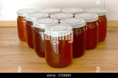 A triangle of honey jars on the table. Fresh honey is packaged in jars. Stock Photo